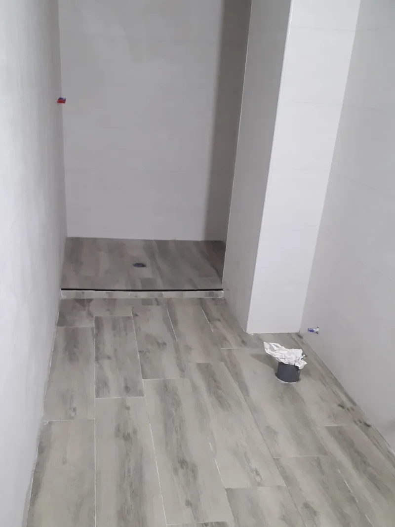Antes: Baño alargado en obra, alicatado y con el plato de ducha de obra, todavía sin sanitarios