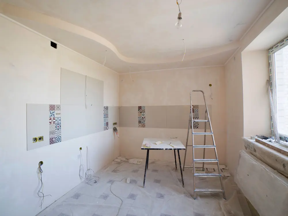 Antes: Cocina en obra con paredes en bruto, escalera y material de construcción (imagen de muestra)