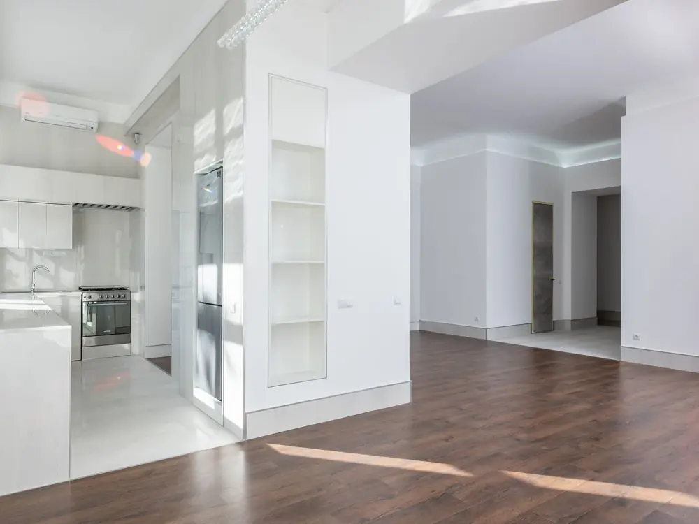 Después: Planta abierta terminada con cocina integrada, suelo de madera y paredes lisas (imagen de muestra)