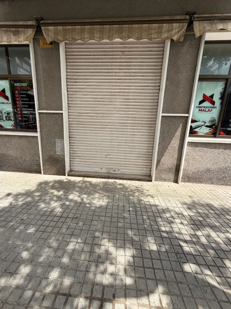 Antes: Fachada de local con la persiana metálica gris y deteriorada
