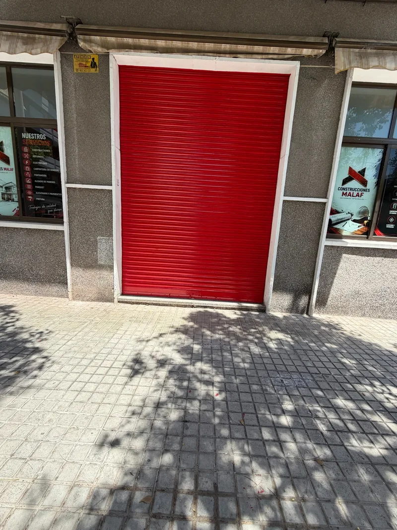 Después: Fachada del mismo local con la persiana lacada en rojo y el marco blanco