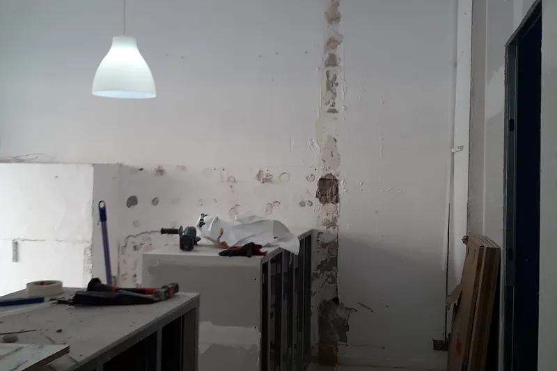 Local en plena reforma: paredes picadas, mostrador de pladur sobre perfilería y herramientas de obra